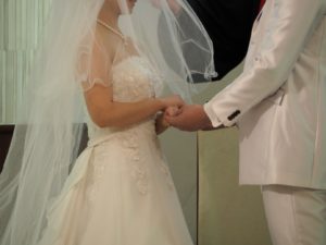 結婚式の挙式で手を取り合う新郎新婦